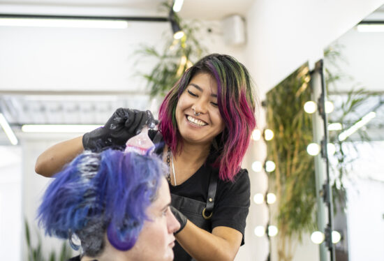 Hairdresser dyeing client's hair at hair salon